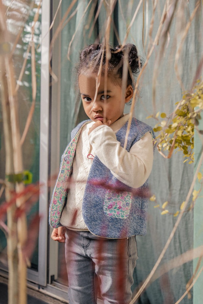 a little girl standing in front of a fence 