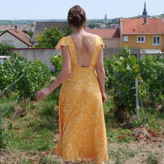 a woman in a dress standing in front of a house 